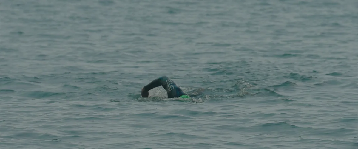 Leo swimming alone in a grey Irish sea, a small figure in open water
